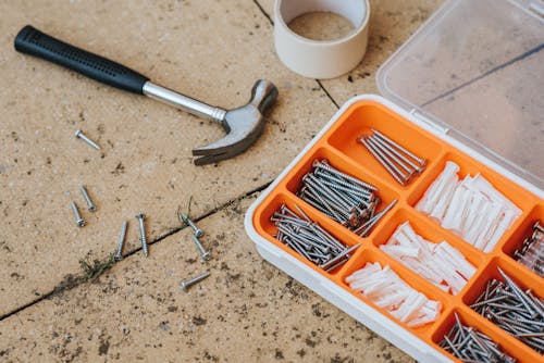 Screws and repair tools in box near hammer