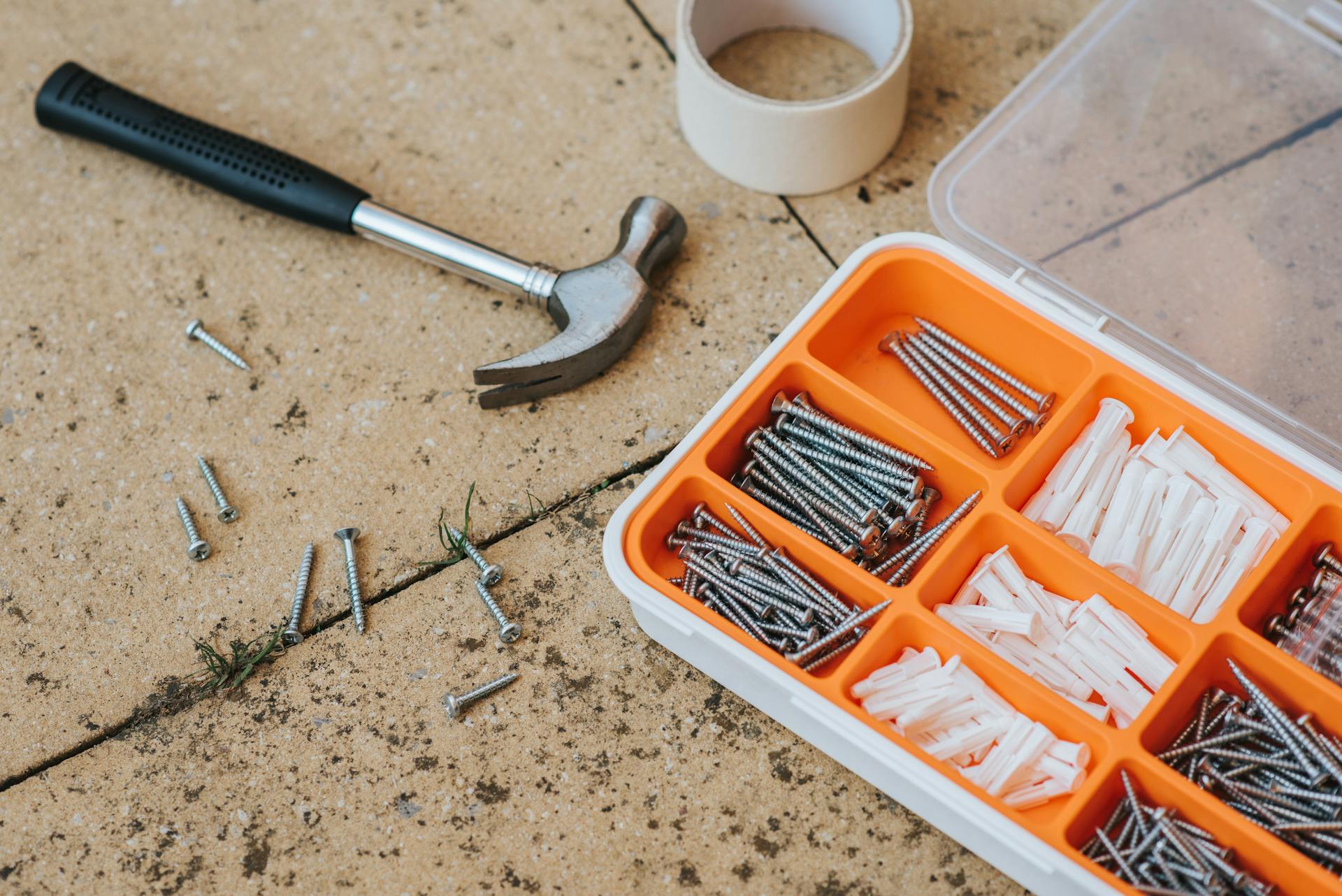 Screws and repair tools in box near hammer