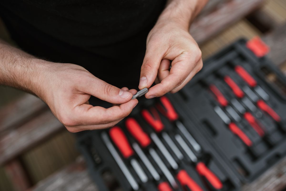 Craftsperson inspecting a screw above an organized toolbox with hand tools