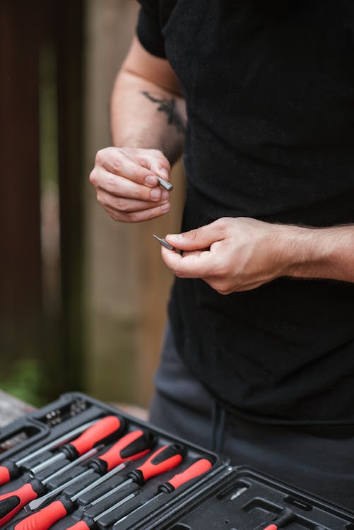 Free Unrecognizable mechanic checking metal details over toolbox with screwdrivers Stock Photo