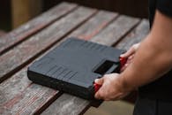 Crop unrecognizable skilled craftsman preparing black toolbox for job on wooden table in soft daylight