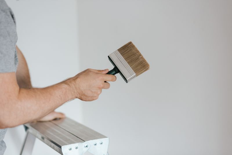 Painter holding a paintbrush while leaning on a stepladder