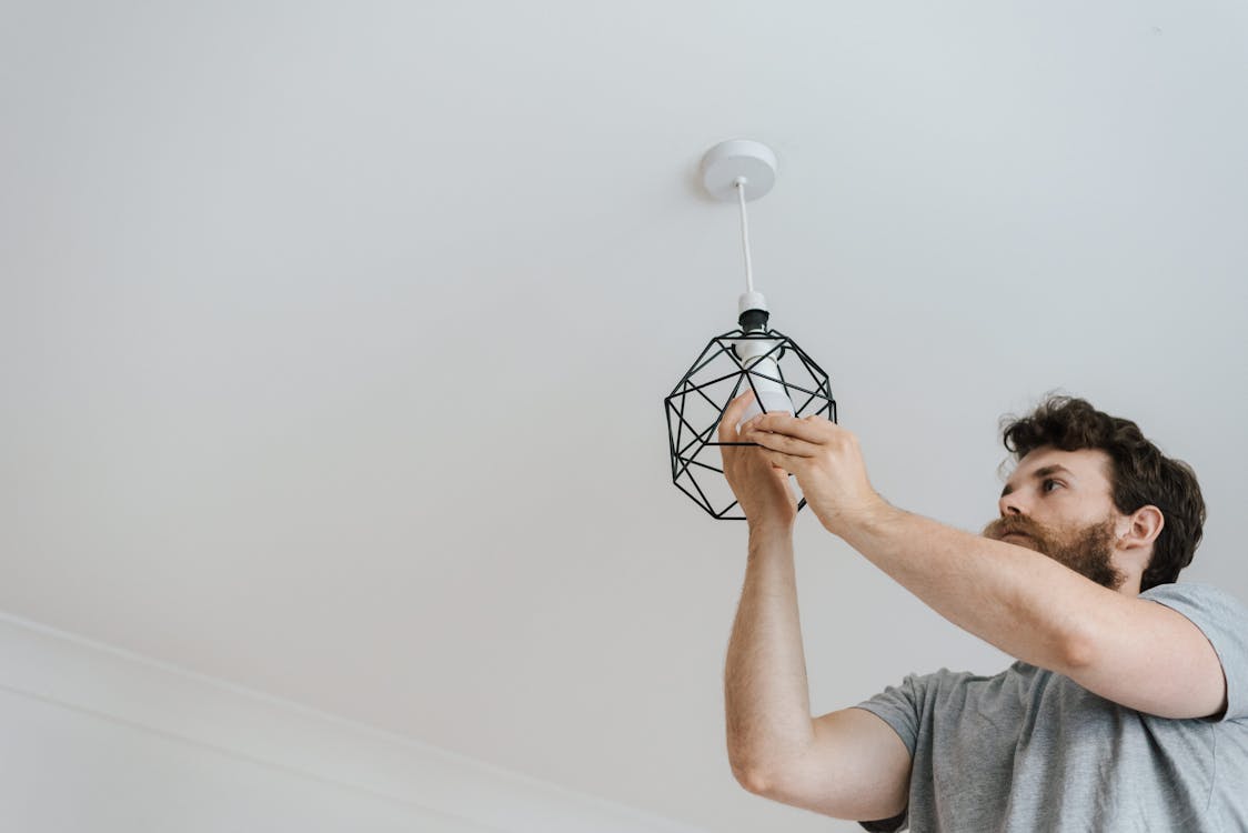 Free Man screwing light bulb into lamp Stock Photo