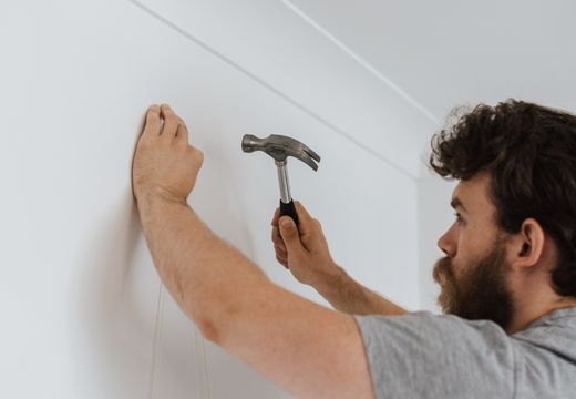 Man using a hammer on a wall during home repairs