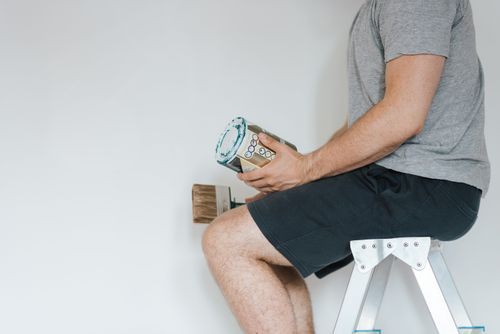 Free Side view of crop anonymous male with professional brush and can of paint near white wall in house Stock Photo