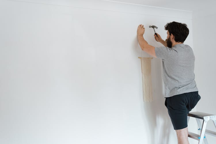 Anonymous Hipster Man Putting Decor On Wall In New House