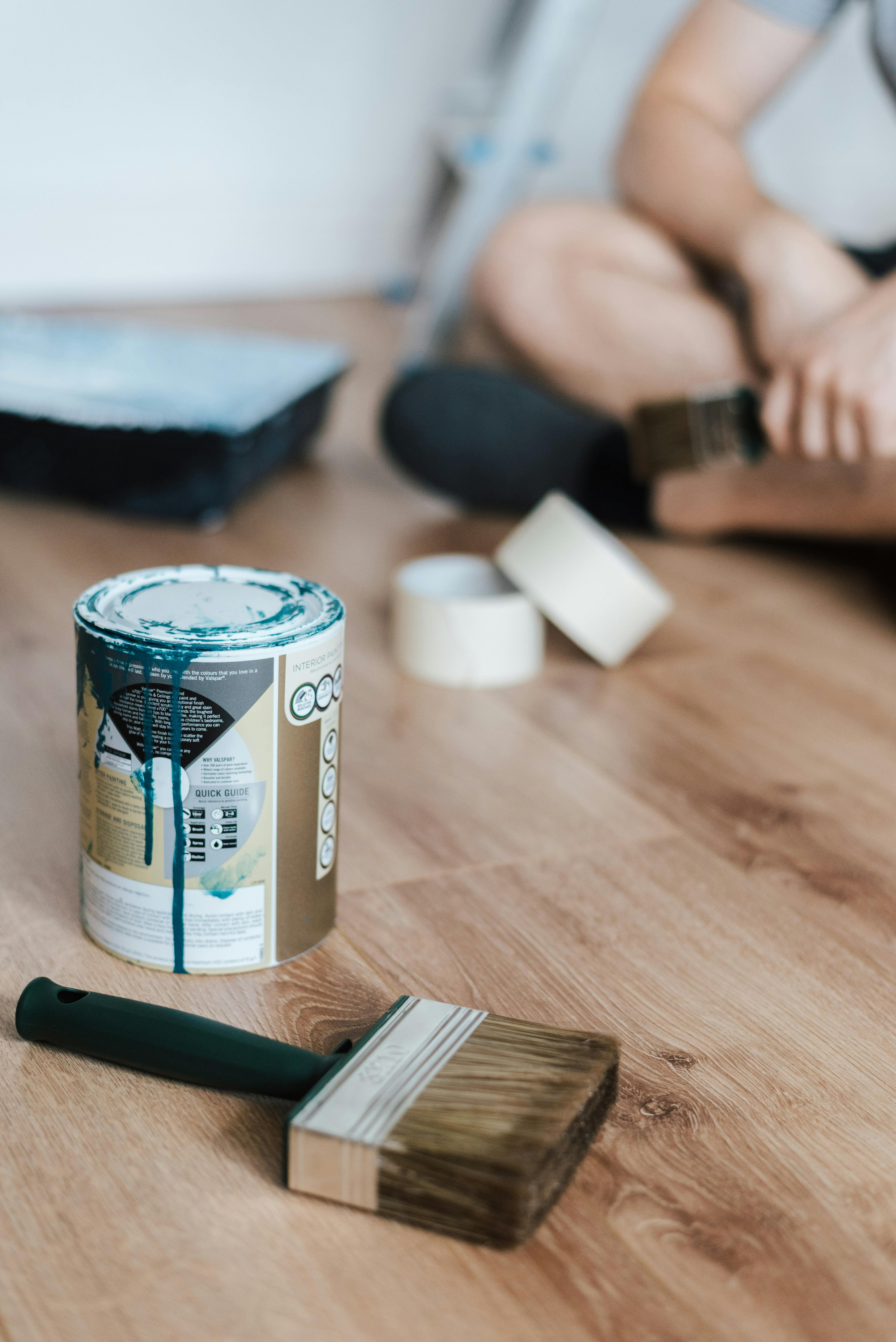 faceless man on floor with can of paint at home