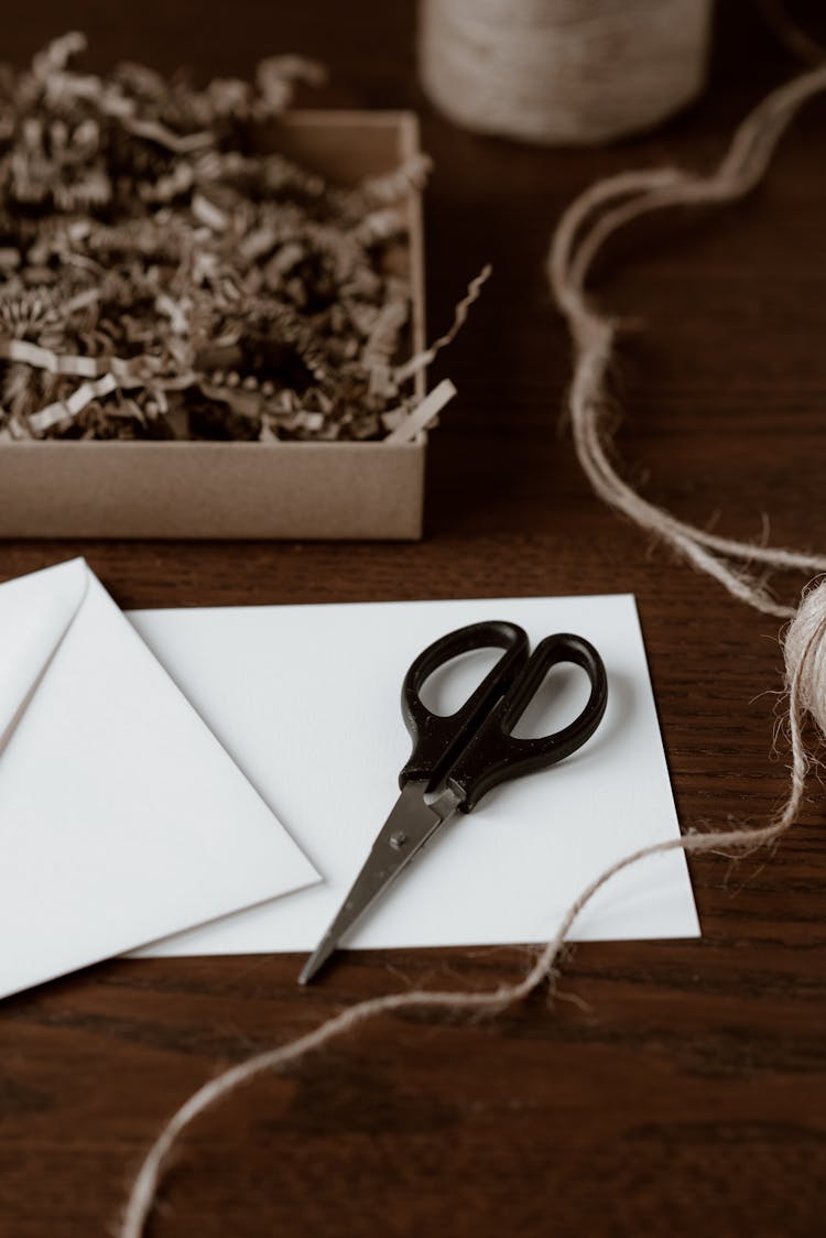 Empty Paper Sheet With Scissors And Thread On Desk