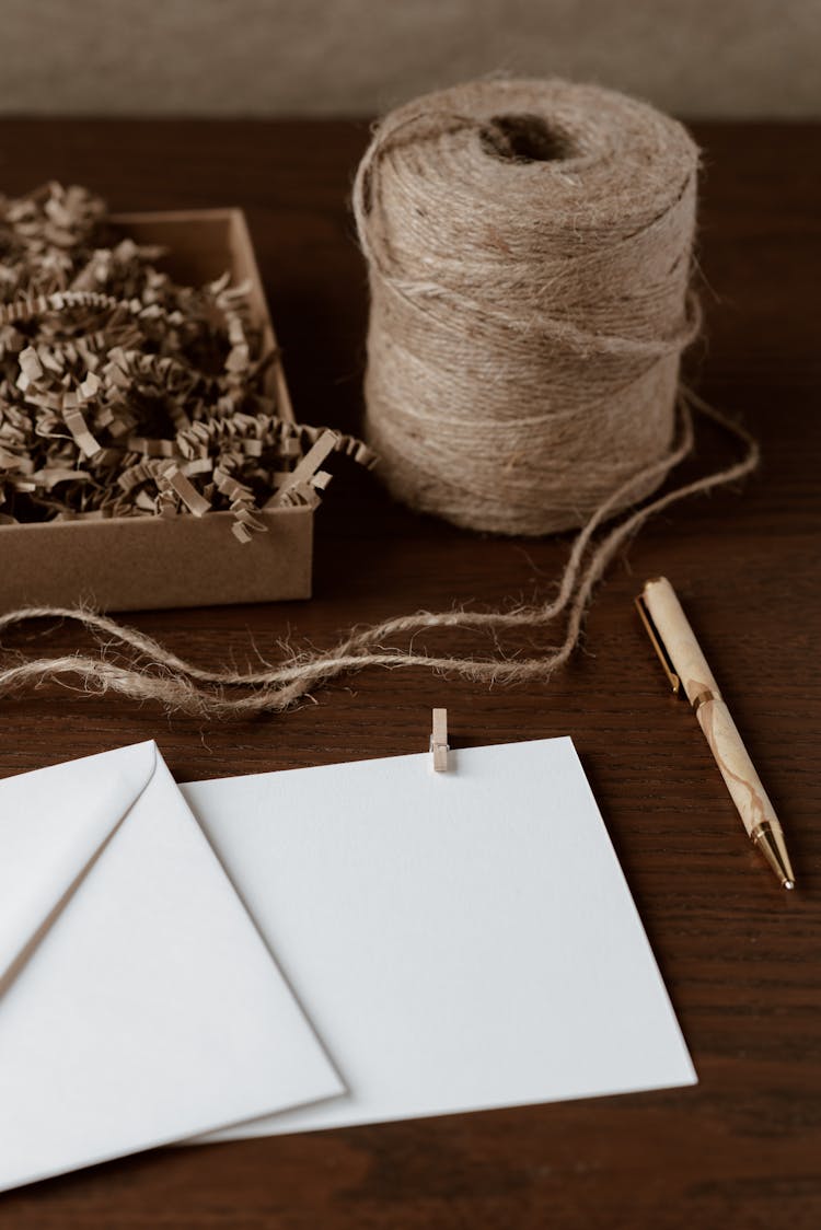 Blank Paper Sheet Near Spool Of Thread On Desk