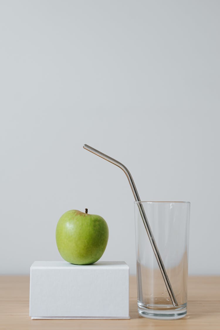 Tasty Apple On Cardboard Box Near Glass With Straw
