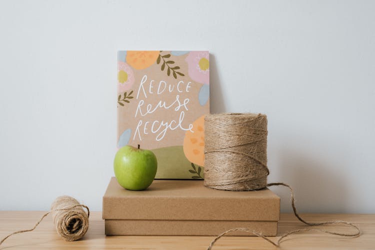 Book On Cardboard Box With Spools Of Threads And Apple