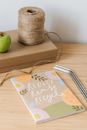 From above of book with Reduce Reuse Recycle inscriptions near spool of thread and apple on carton box on white background