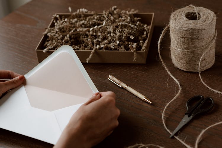 Crop Unrecognizable Woman Opening Envelope Above Desk With Twine