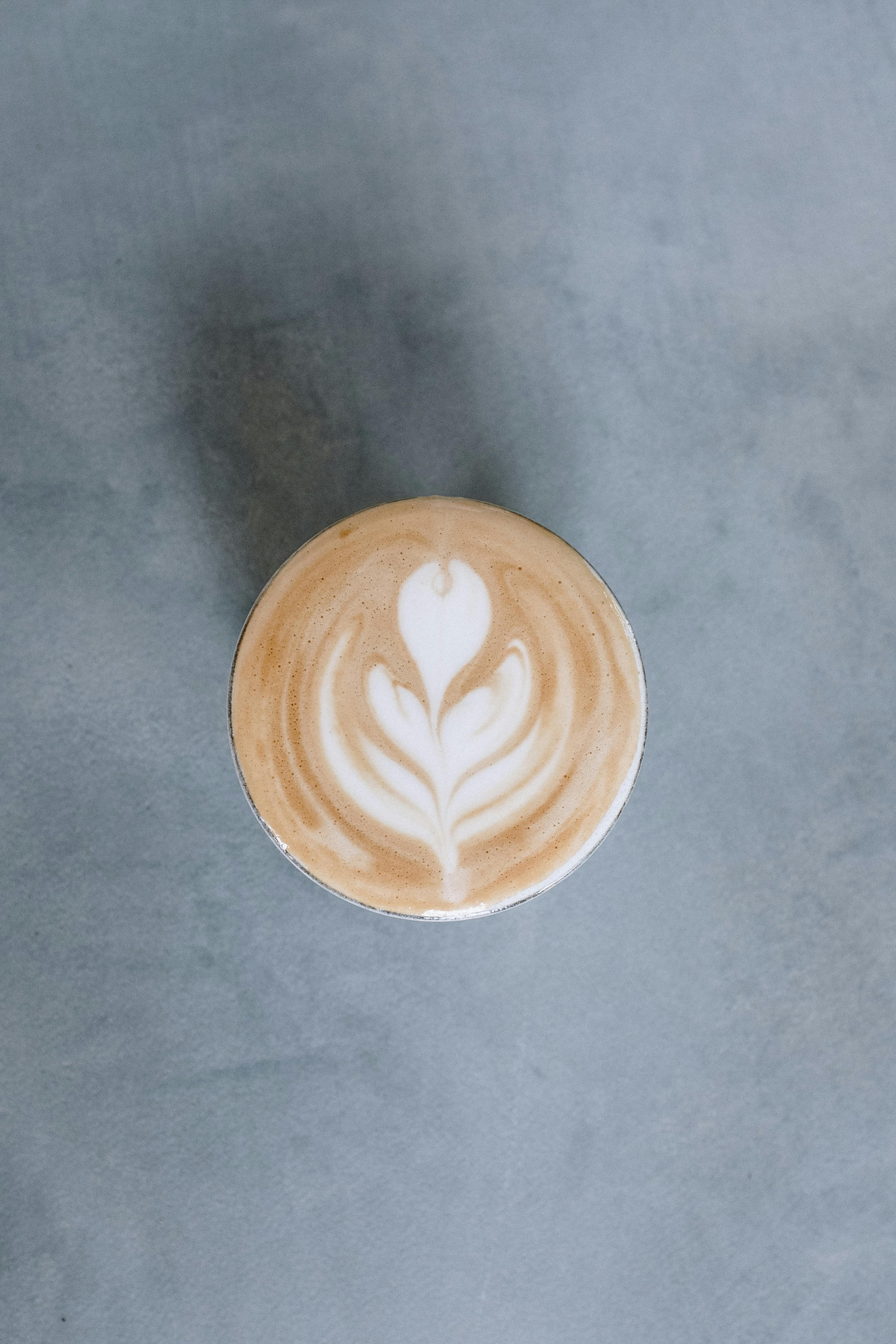 在一个极简主义背景上，一个咖啡杯的顶视图展现了典雅的拿铁艺术