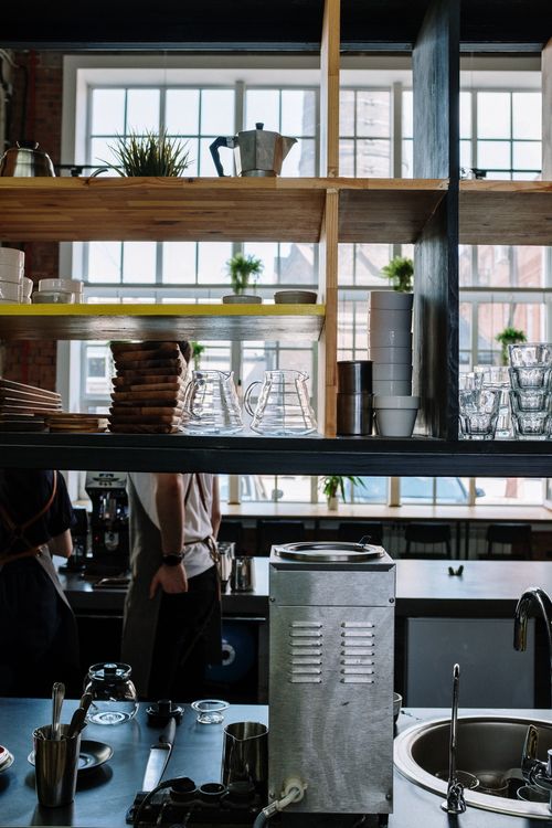 Free A stylish coffee shop interior featuring open shelves, coffee equipment, and modern decor. Stock Photo