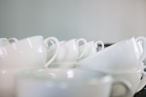 Free Stacked white coffee cups create a minimalist still life in a café. Perfect for beverage and hospitality themes. Stock Photo