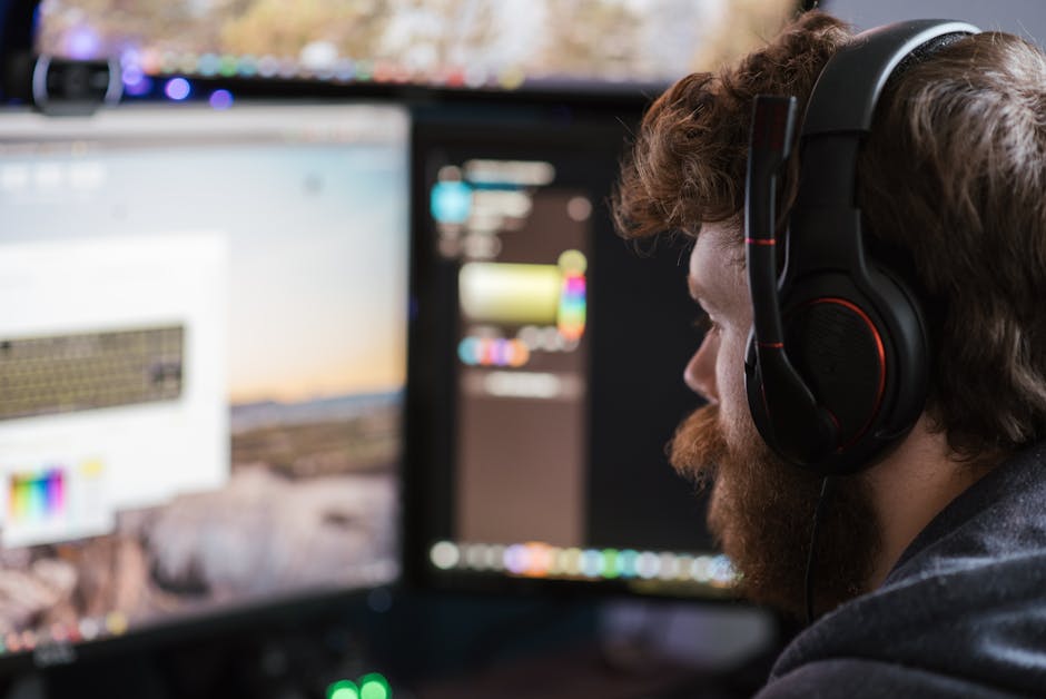 Man with headset concentrating on work at dual monitors in a home office setting.