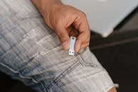 一名穿着牛仔裤的匿名男性坐在笔记本电脑附近，展示着来自农作物上方的闪存驱动器