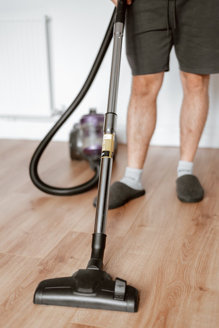 Man Vacuuming Floor With Cleaner In Home