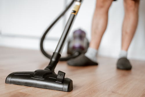 Free Man cleaning floor with vacuum cleaner Stock Photo