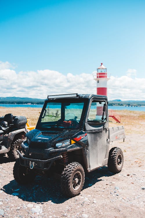 Old ATV on sandy sea shore behind lighthouse