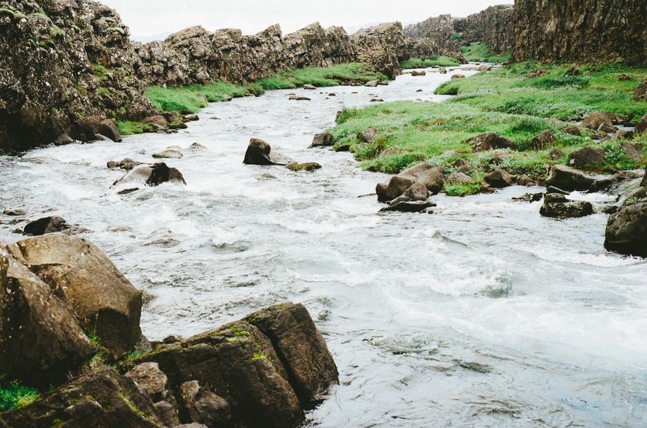 A tranquil stream meandering through a rocky landscape, surrounded by lush greenery.
