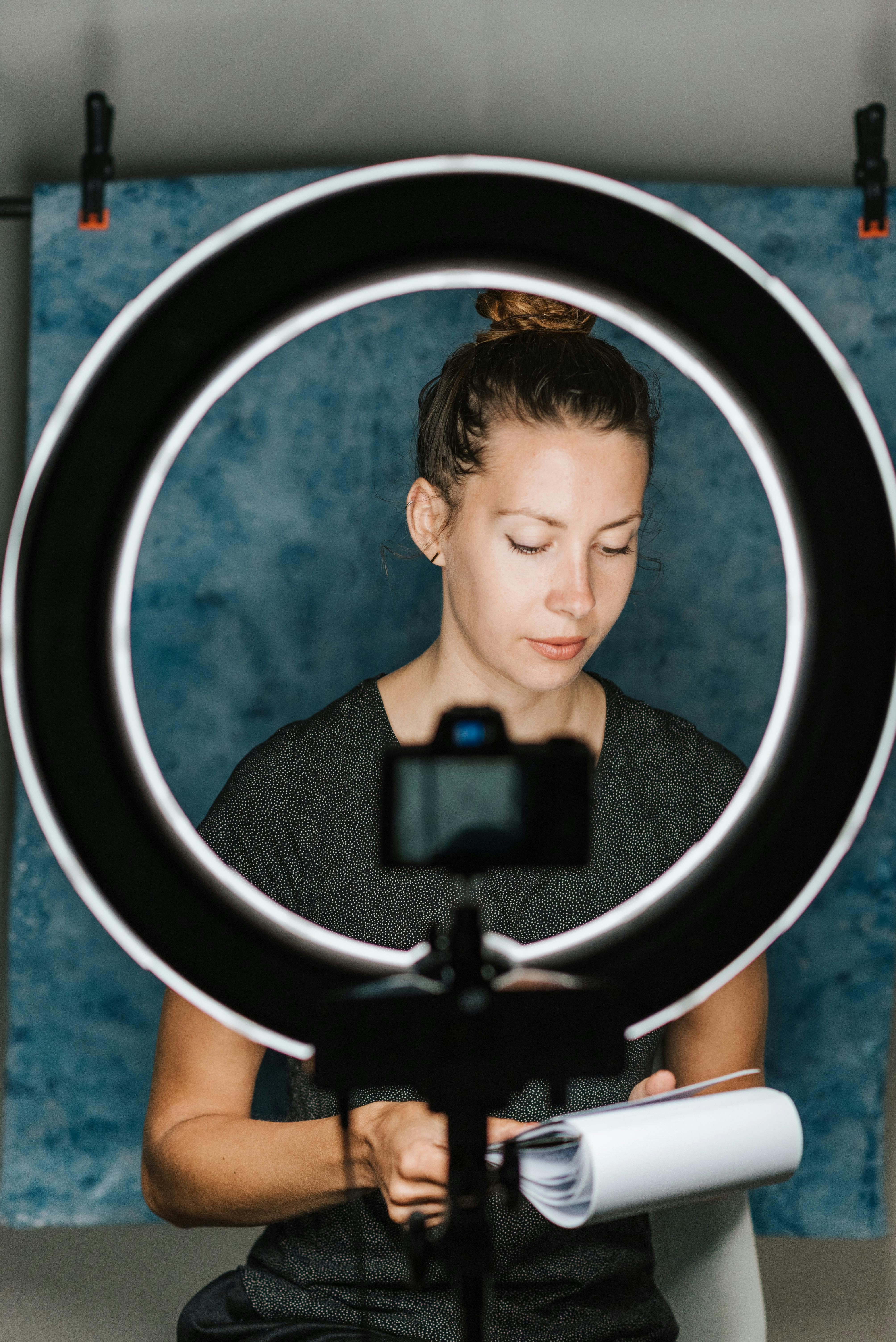 Young female examining notes in notebook in professional studio with photo camera and studio lamp