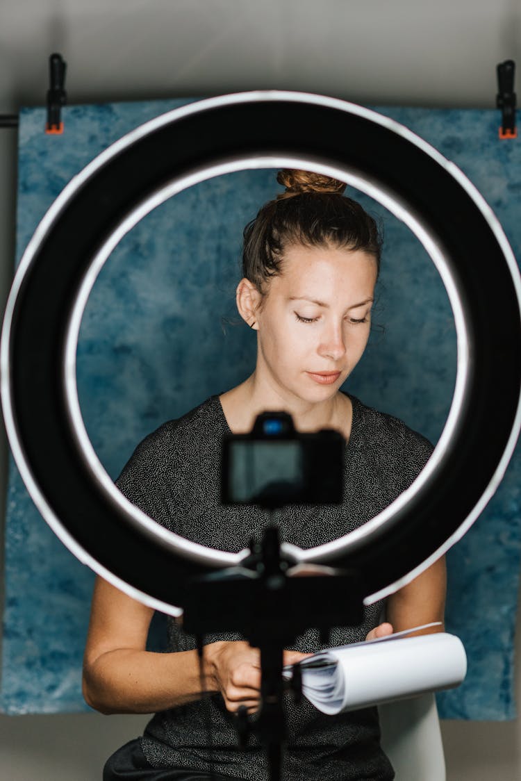 Young Woman Reading Scenario Near Digital Camera And Studio Lamp