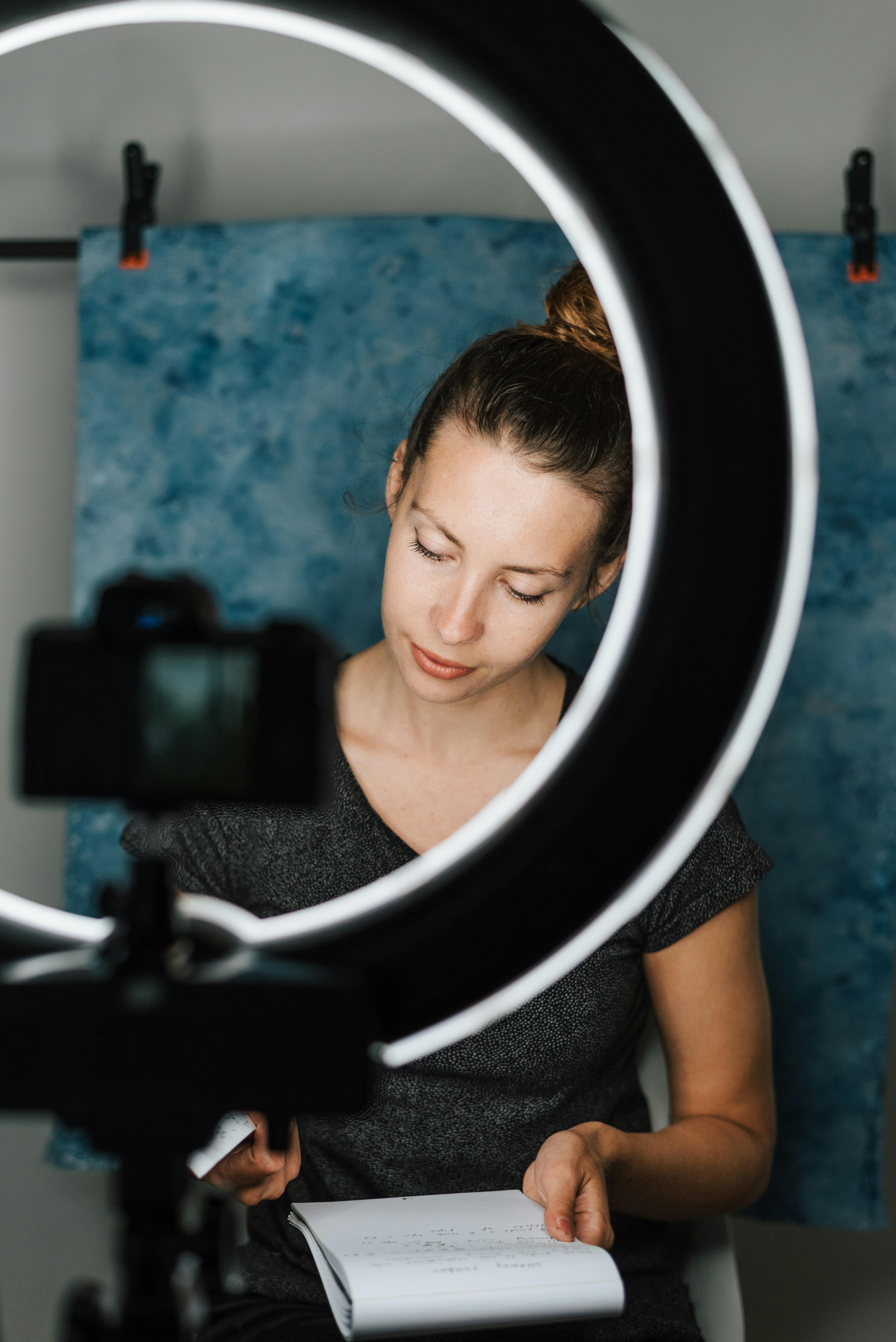 woman checking notebook near photo camera and studio lamp