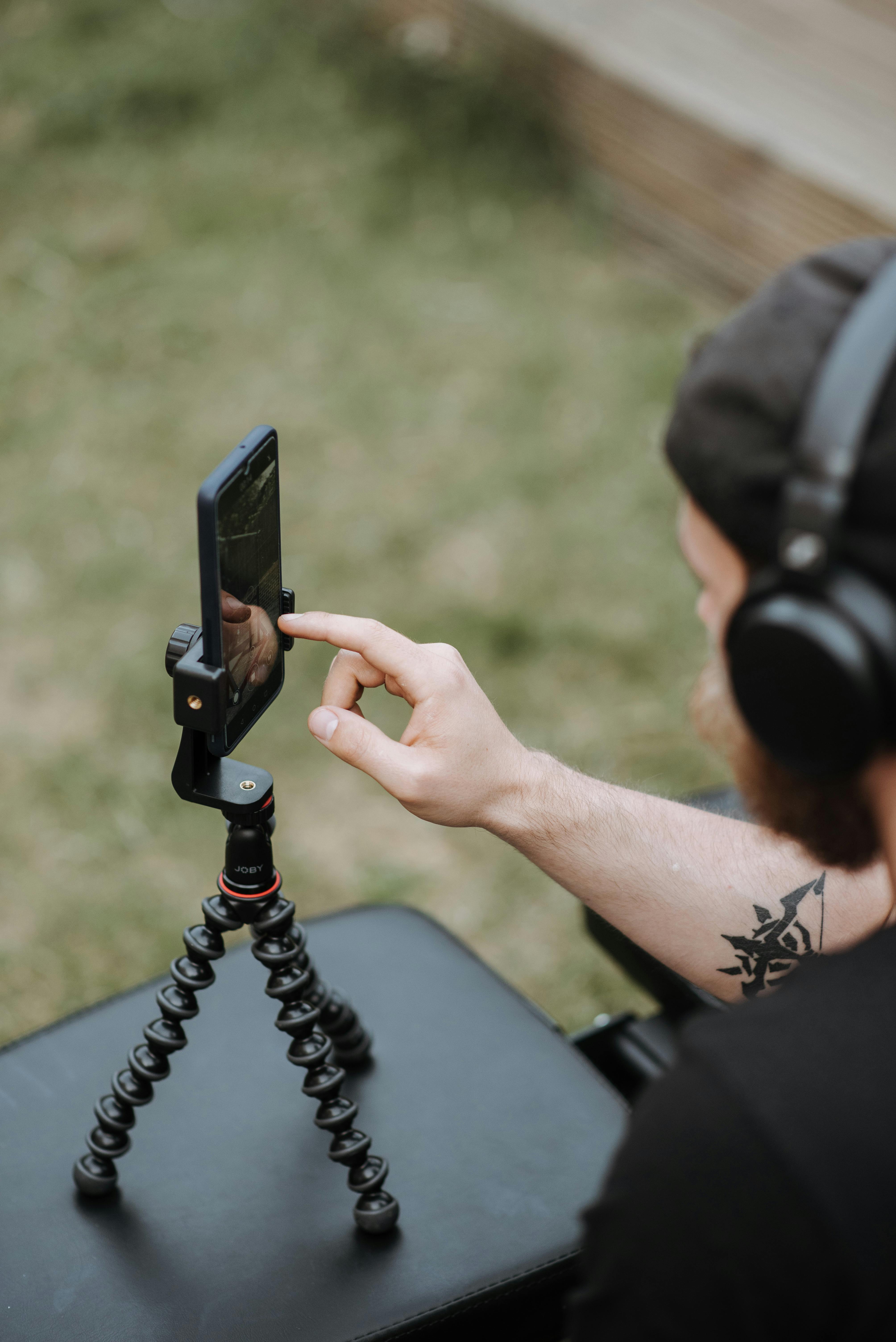 man recording video on smartphone with tripod