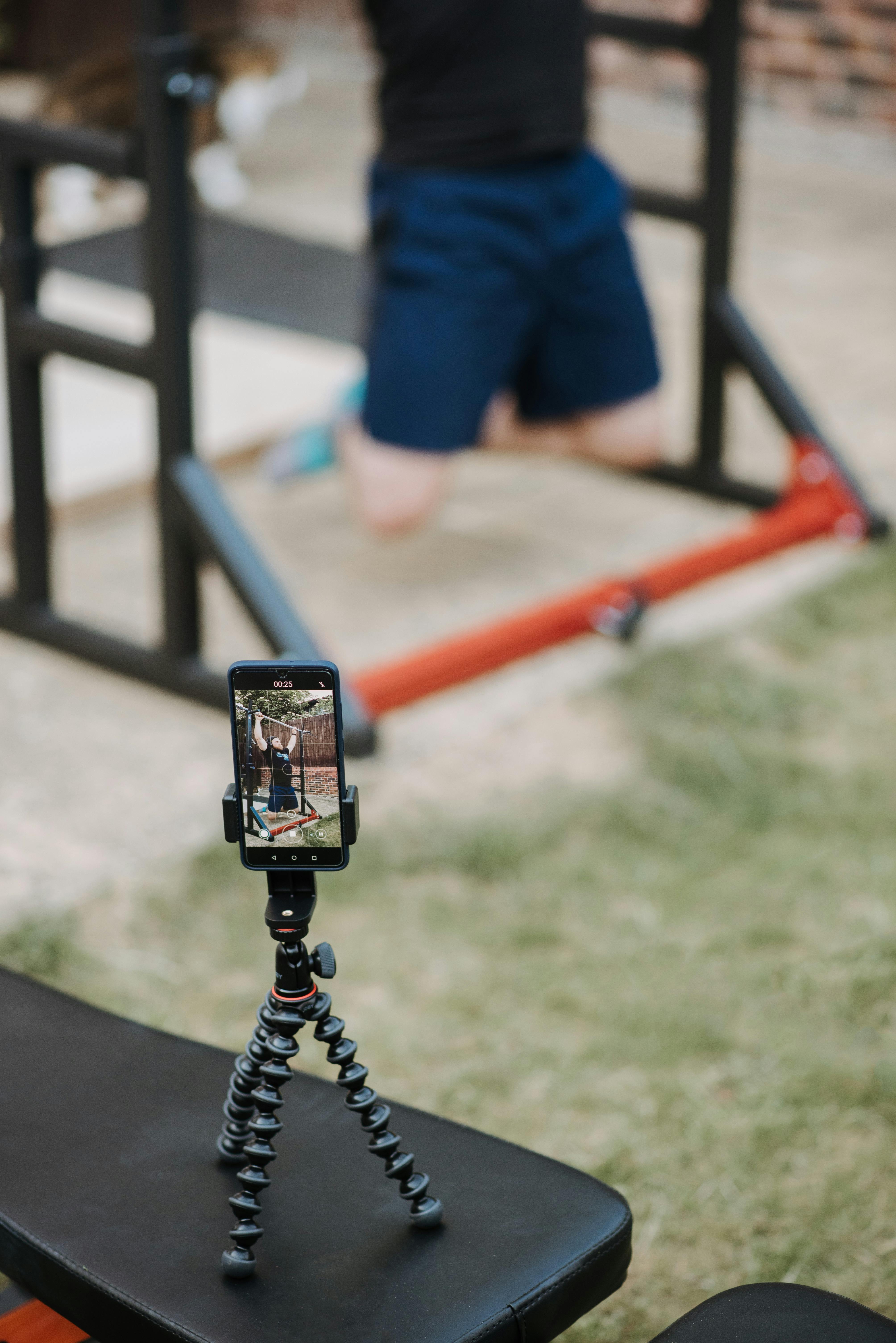 man recording video of training on horizontal bar