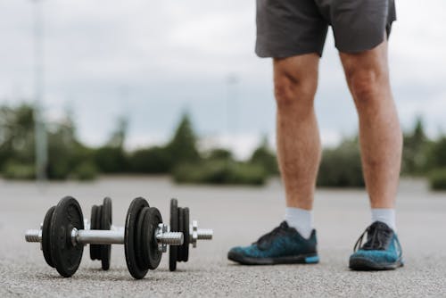 Free Man in activewear standing near dumbbell Stock Photo