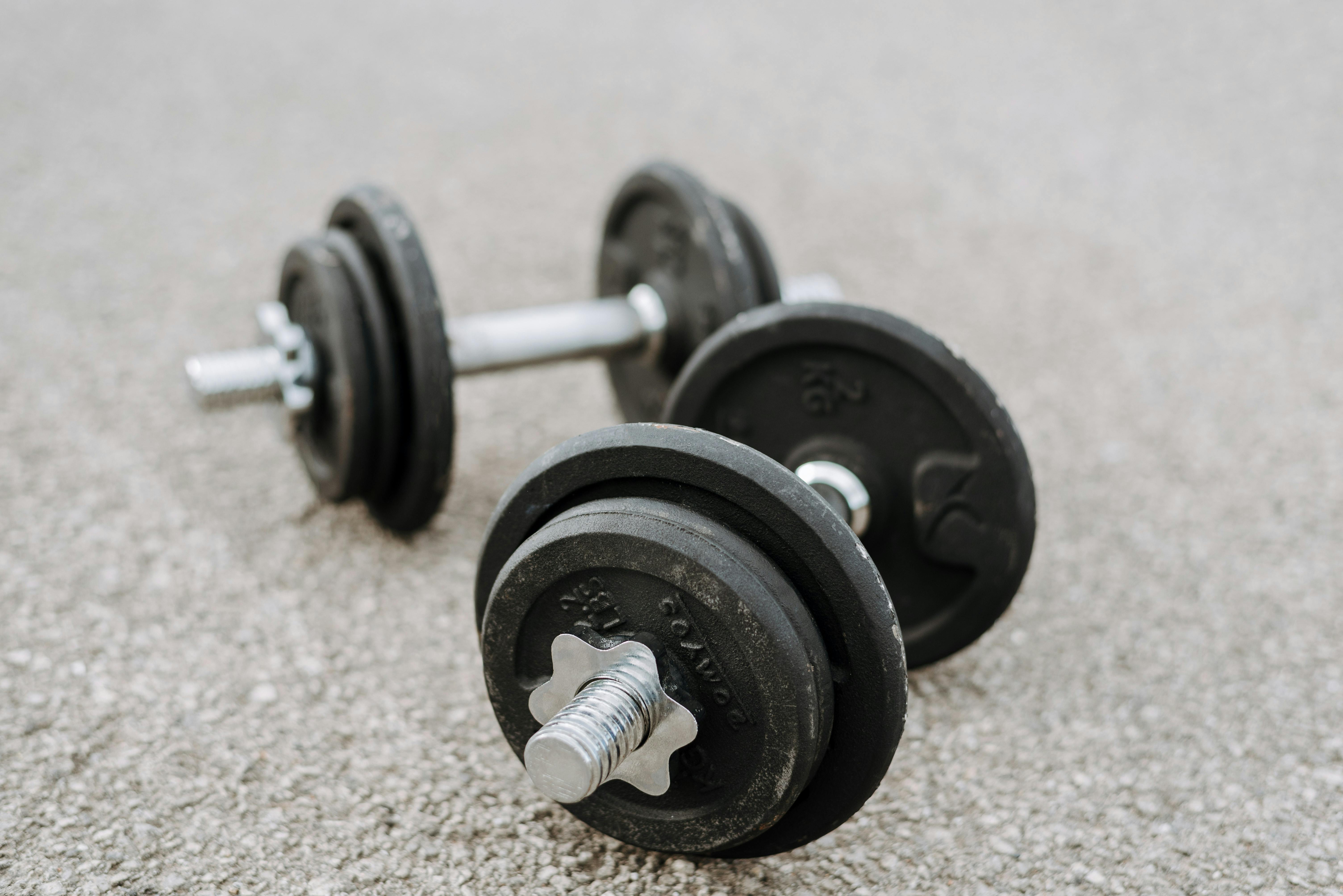 heavy iron dumbbells placed on asphalt road