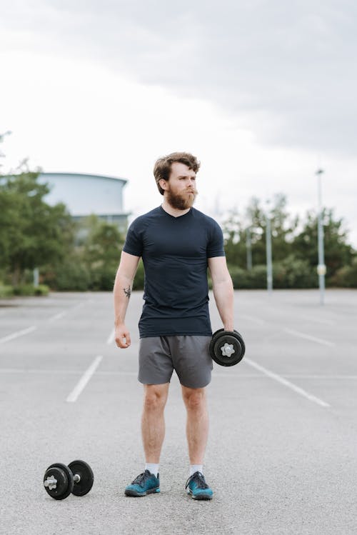 Sportsman with dumbbells training on sports ground