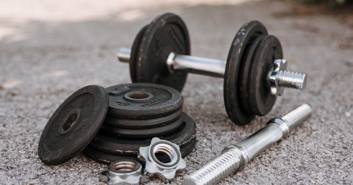 An adjustable dumbbell with spare weight plates on concrete