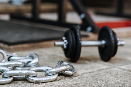 Metal chain and dumbbell on tiled pavement