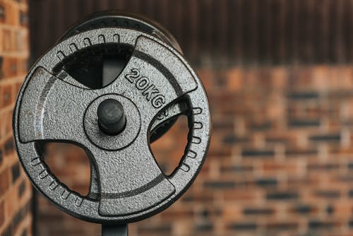 Modern black dumbbell with circle shaped plates indicating weight number on solid surface in daylight