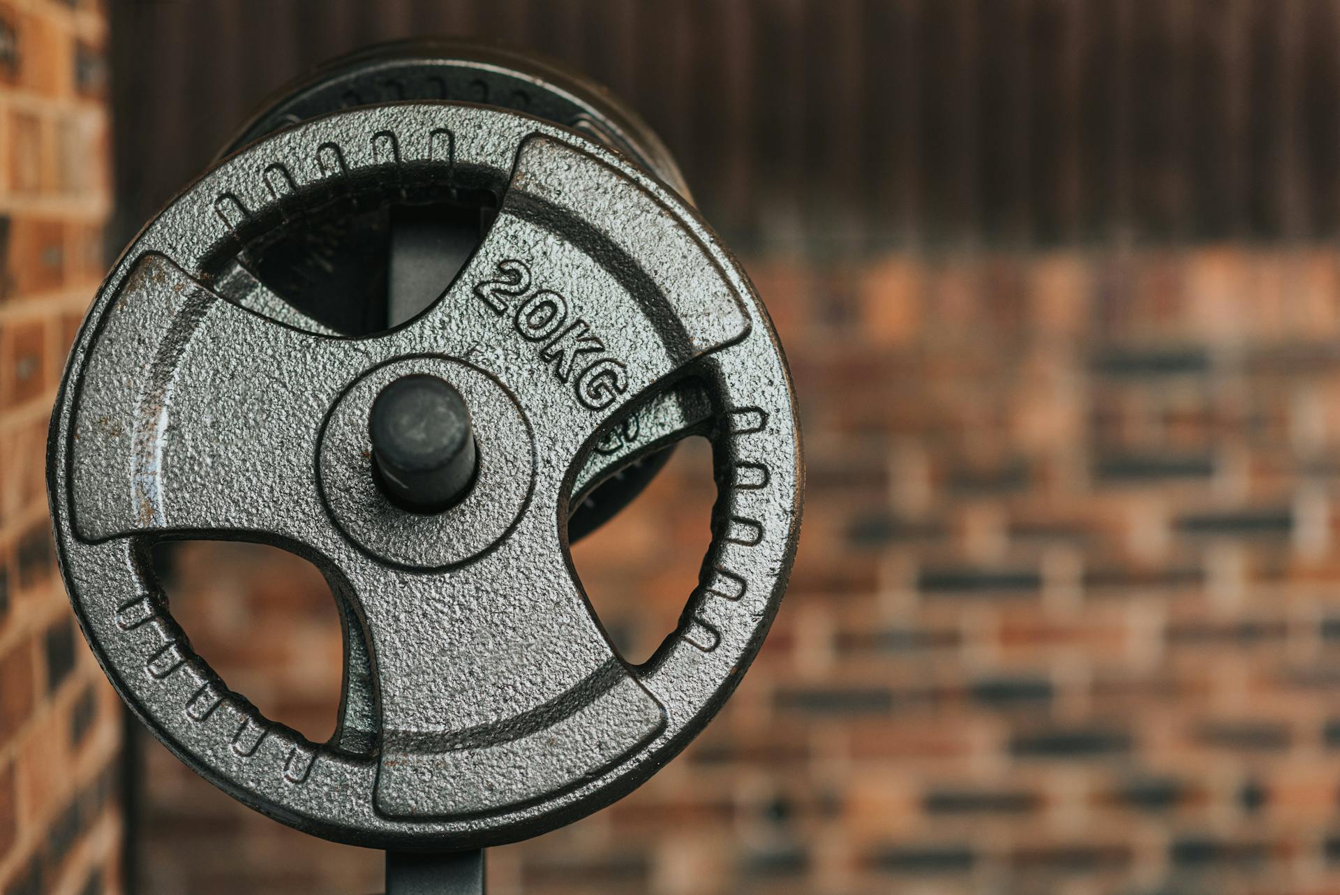 Modern black dumbbell with circle shaped plates indicating weight number on solid surface in daylight