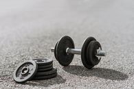 Dumbbell near pile of plates on pavement in sunlight