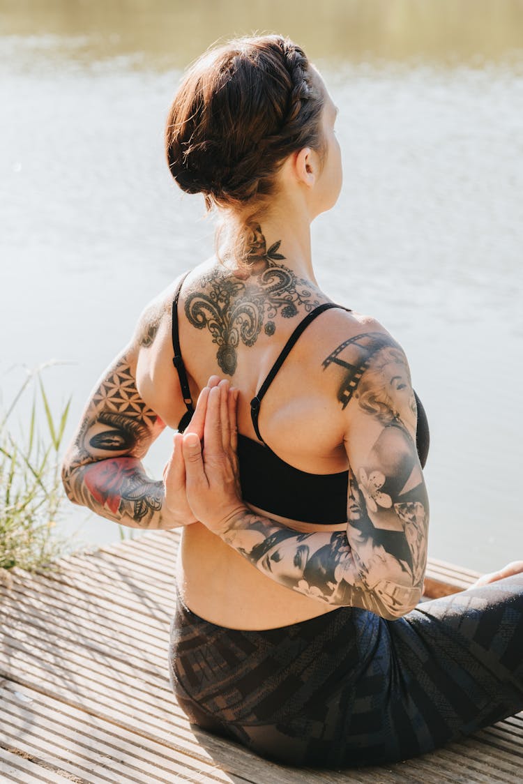 Anonymous Tattooed Woman Meditating In Reverse Prayer Pose