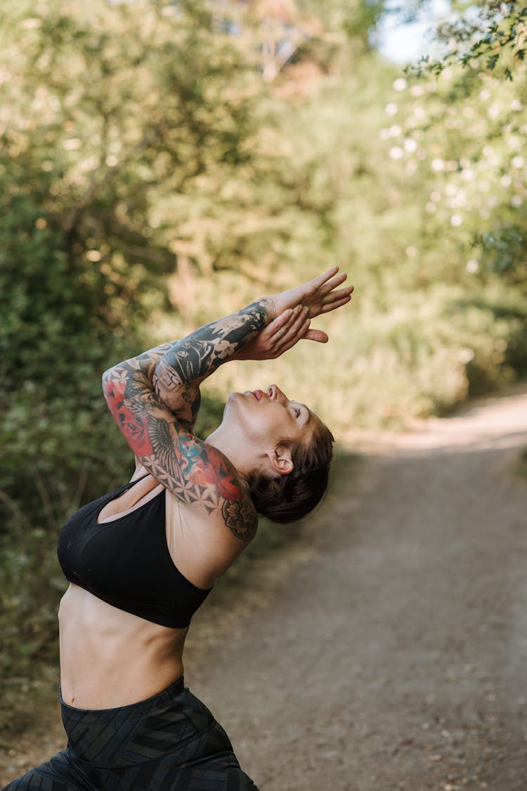 Tattooed Woman Practicing Yoga On Walkway In Summer