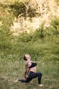 Tattooed woman stretching arms while practicing yoga on meadow
