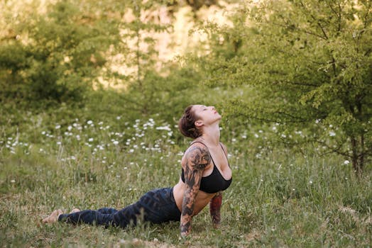 Side view of young reflective female with closed eyes standing in Bhujangasana pose while practicing yoga on meadow
