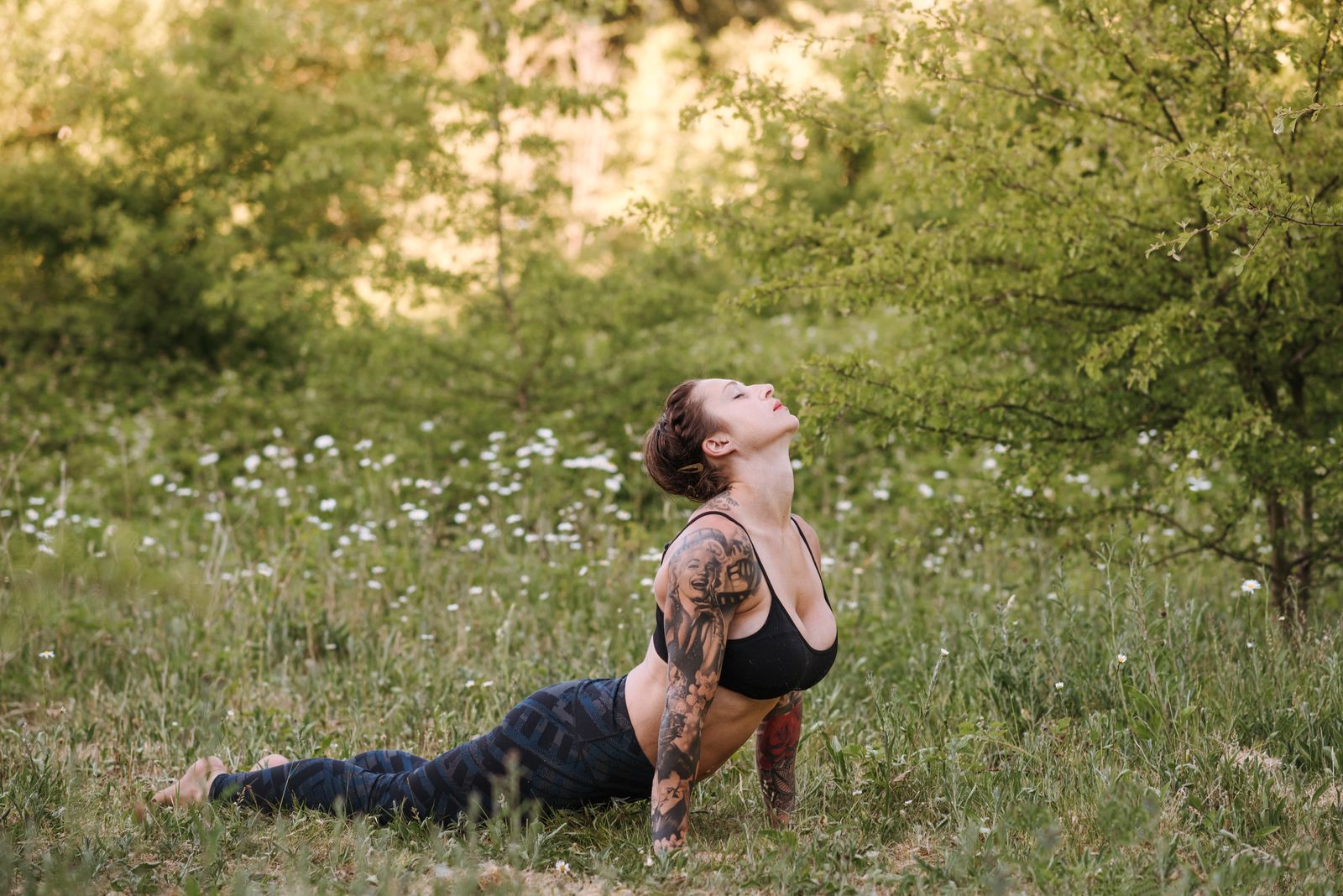 Woman performing a high cobra pose backbend outdoors on grass