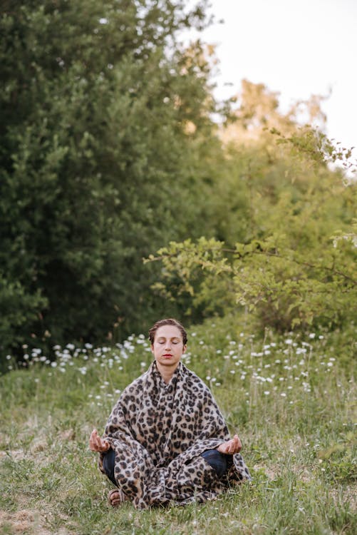 Concentrated woman meditating in Lotus pose on meadow