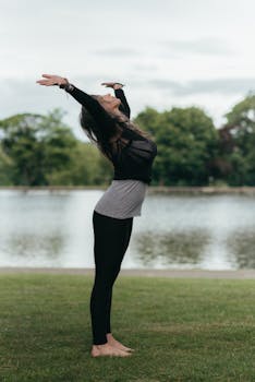 一位女子在宁静的湖边摆出瑜伽姿势，展现宁静与正念