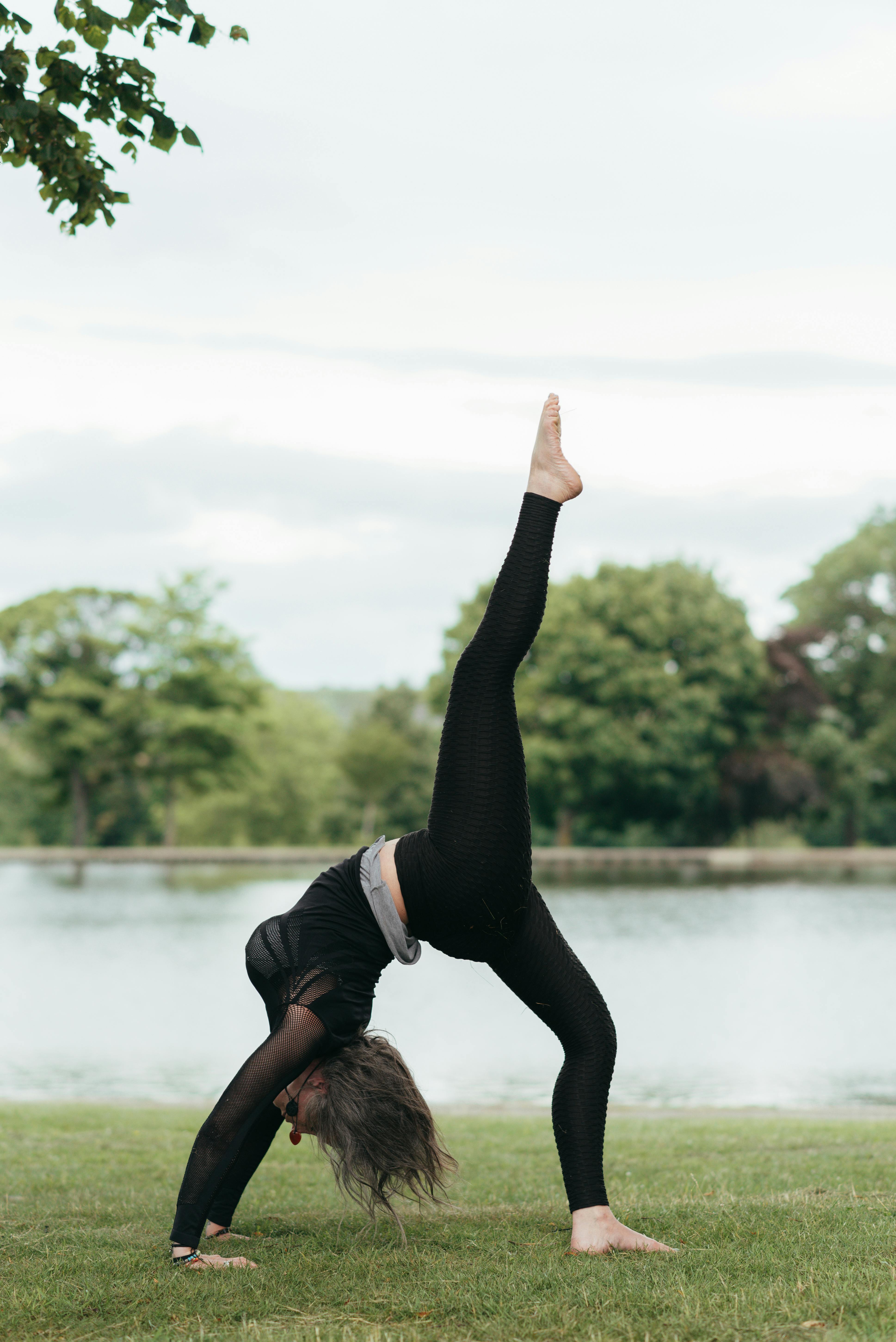 Flexible woman doing bridge pose with leg raised · Free Stock Photo