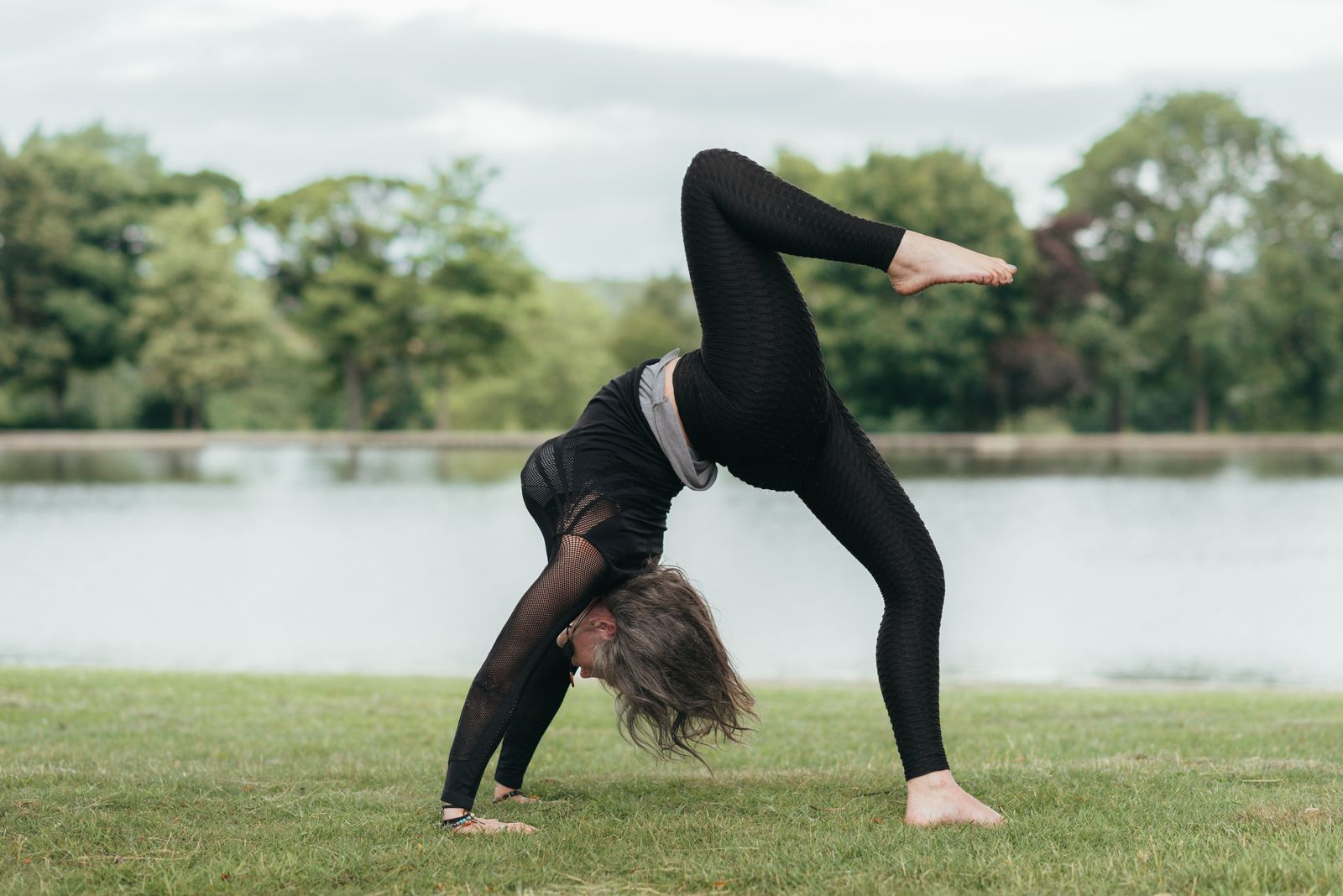 Woman practicing Chakrasana wheel pose backbend on a yoga mat