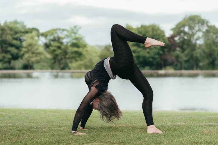 Unrecognizable Woman Showing One Legged Wheel Pose On Coast