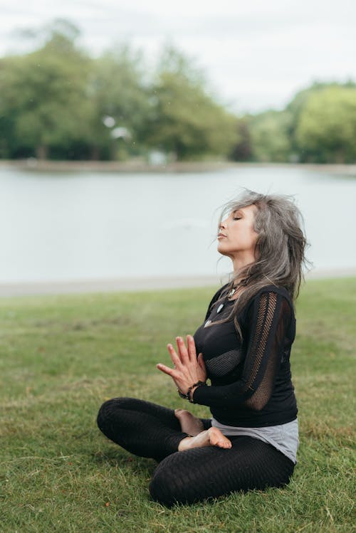 Mindful woman meditating with praying hands in Lotus pose